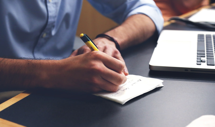 Male hands writing on pad of paper