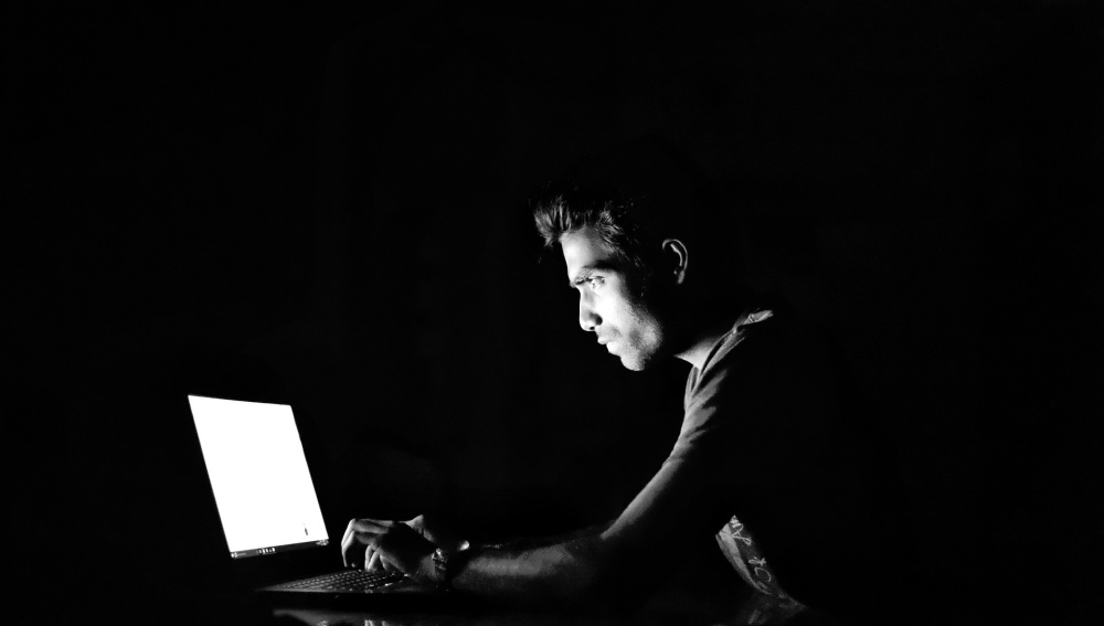 man on computer in the dark